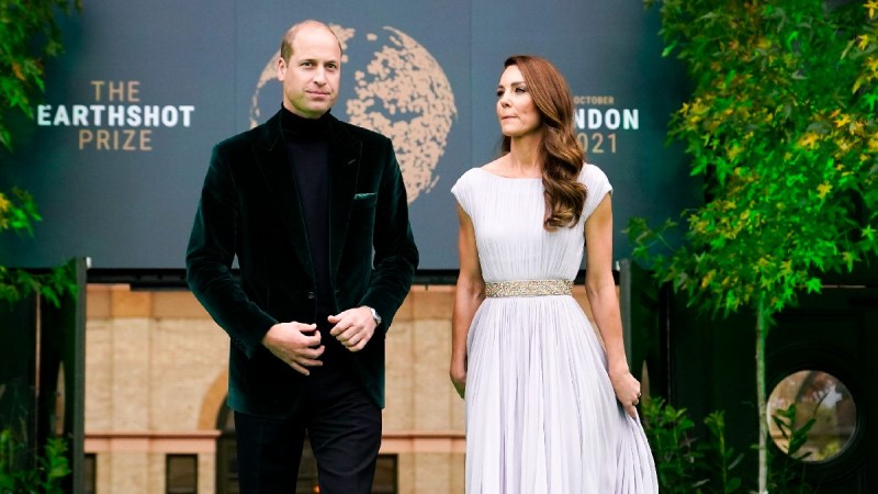 Prince William wears a green velvet jacket and stands with wife Kate Middleton, in a lilac dress