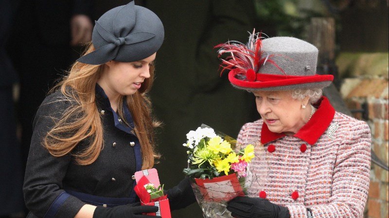 Princess Beatrice, in a dark coat, looks at flowers with Queen Elizabeth, in a red coat