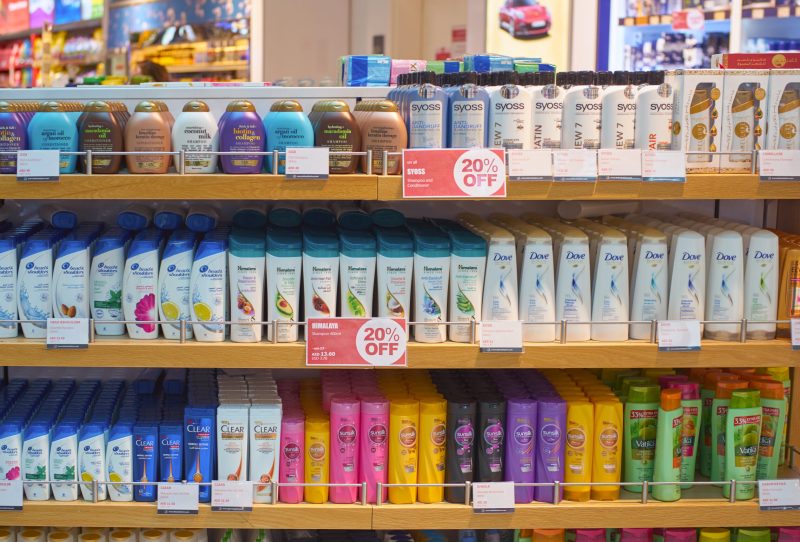 Store shelf full of shampoo and conditioners from various drug store brands.
