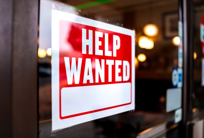 'Help Wanted' sign hanging in a store window.