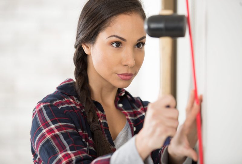 Woman concentrating with hammer in hand.