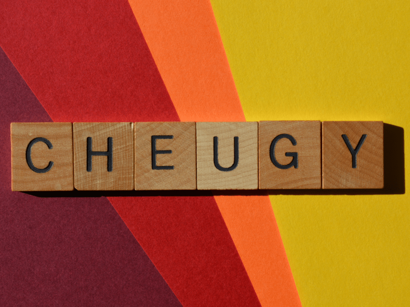 Scrabble letters spelling out the word 'cheugy' on a warm background