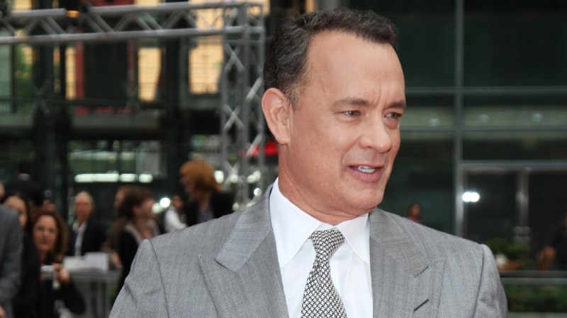 Tom Hanks wears a gray suit as he walks the red carpet outdoors