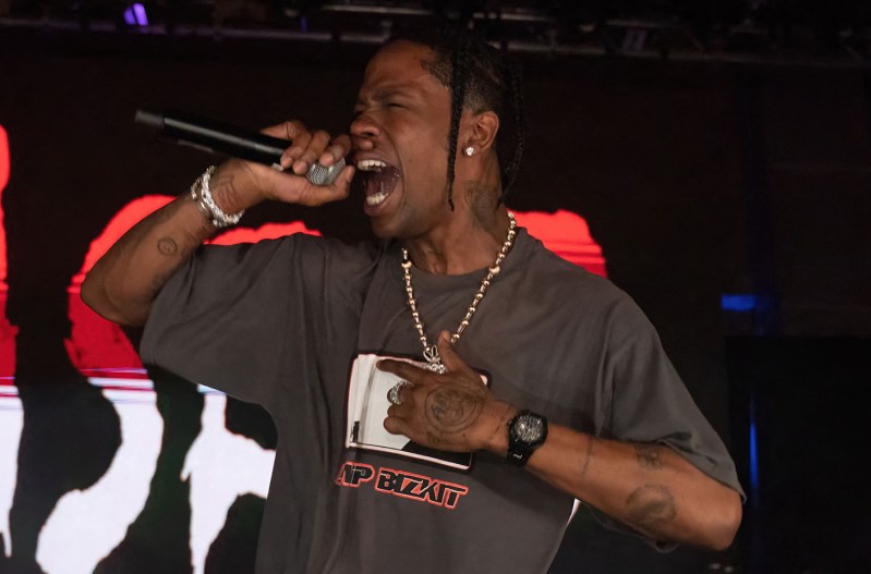 Travis Scott screaming into a microphone on stage
