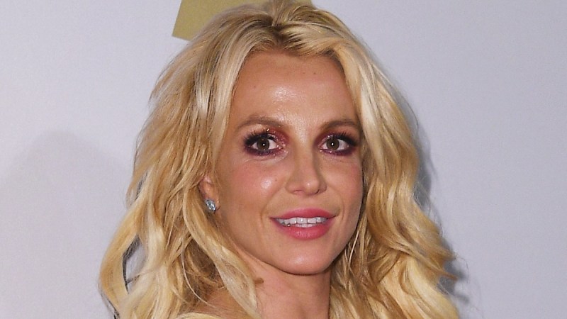 Britney Spears wears a silver dress and stands on the red carpet