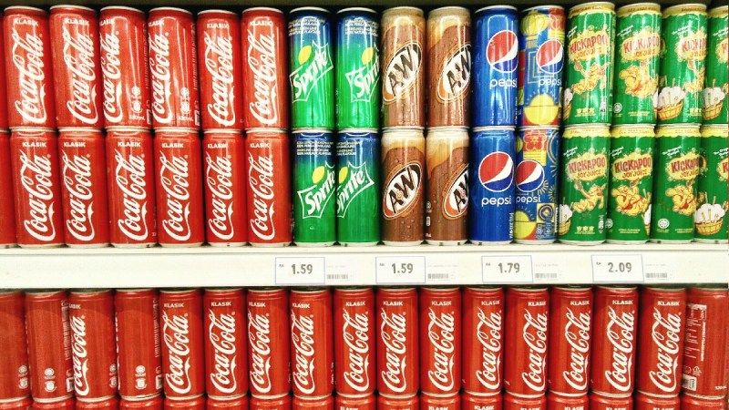 Cans of Coca-Cola brand products on a grocery store shelf