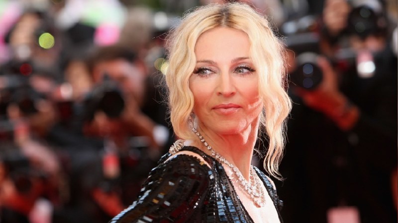 Madonna wears a black dress and looks over her shoulder on the red carpet