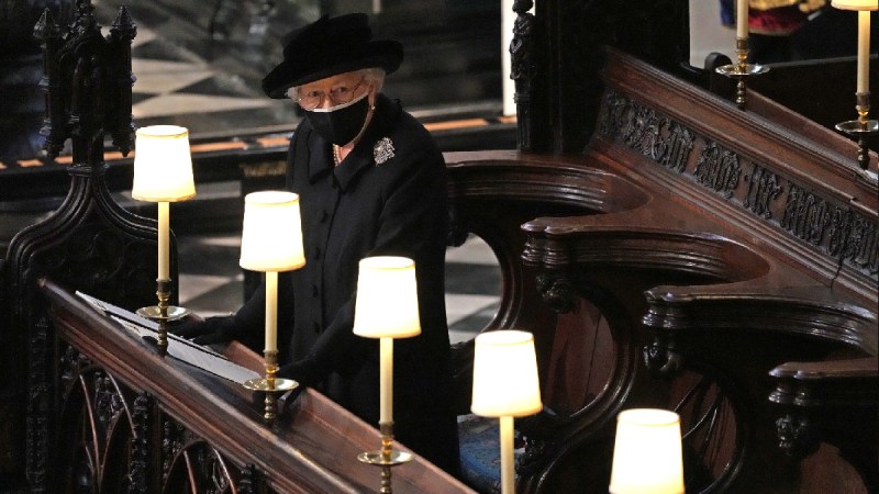 Queen Elizabeth wears a black dress, hat, and face mask at the funeral of her husband Prince Philip