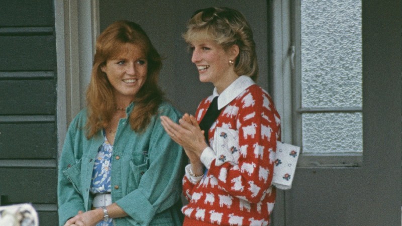 Sarah Ferguson, in a green top, stands with Princess Diana, in a red sweater