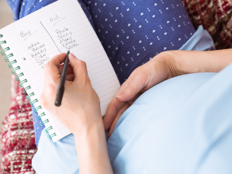 Pregnant woman listing baby names at home in the living room