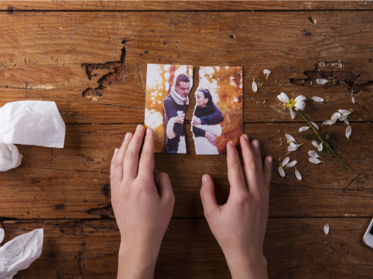 Unrecognizable sad woman holding torn picture of couple in love.
