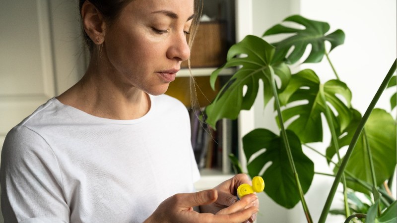 A woman wearing a white t shirt applies balm to her hand indoors
