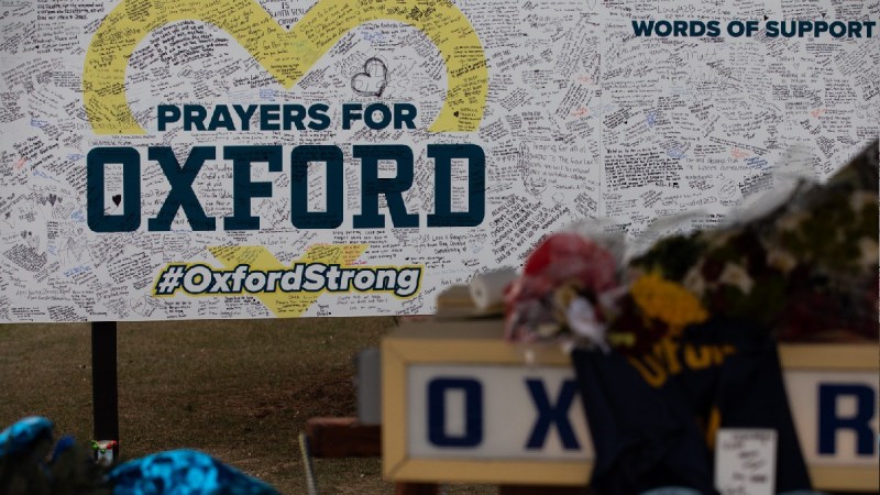 A board covered in supportive messages makes up the background of an Oxford memorial