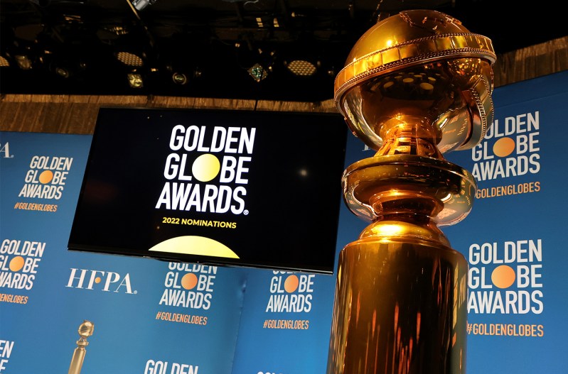 A Golden Globe in the foreground in front a of TV with "Golden Globes Awards" graphic on it.