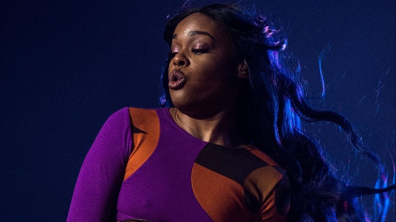 Azaelia Banks wears a purple and orange ensemble as she performs onstage