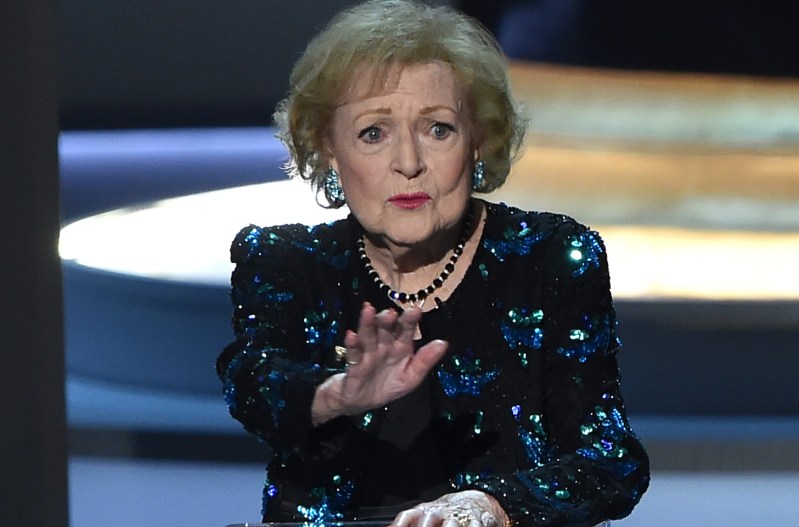 Betty White at a dais, hold her hand up as if to say "stop"