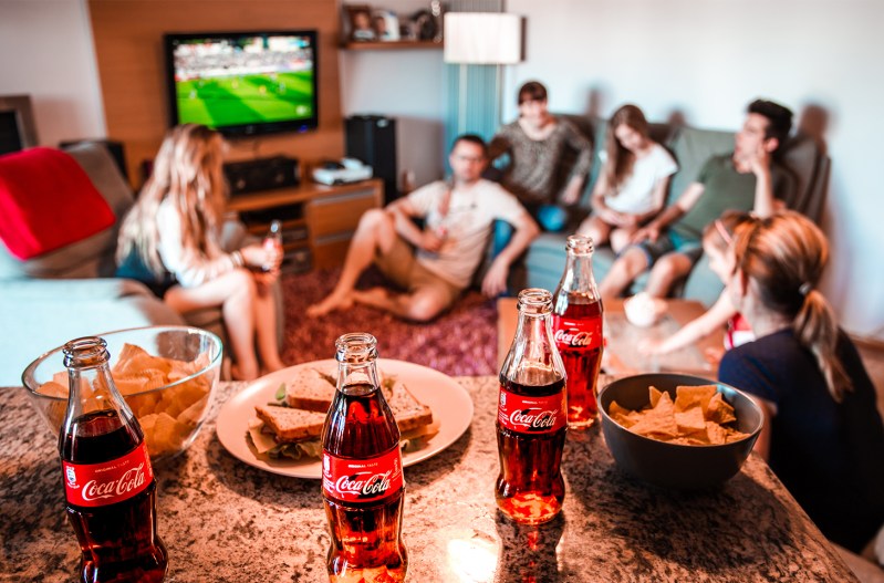 A party with coca-cola being served with a tv on football in the background