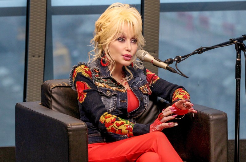 Dolly Parton seated, speaking into a microphone on a radio show