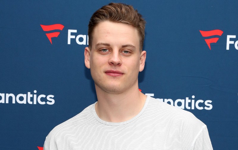 Joe Burrows wears a white stripped shirt in front of a blue background on the red carpet