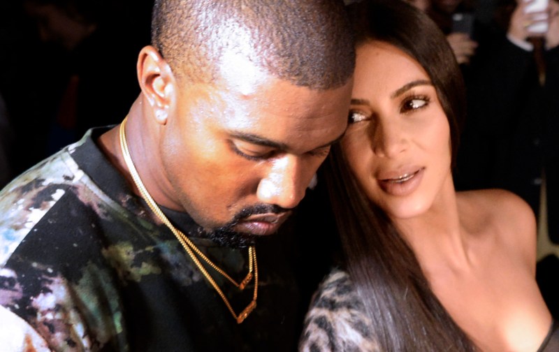 Kanye West and Kim Kardashian sit closely together during a fashion show