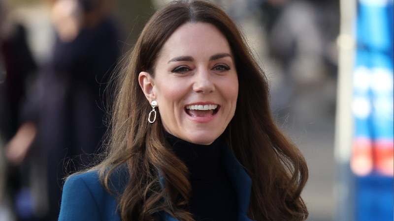Kate Middleton wears a blue coat over a black sweater during a royal event