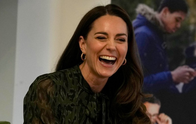 Kate Middleton wears a green and black dress and laughs during a royal visit to a mental health charity
