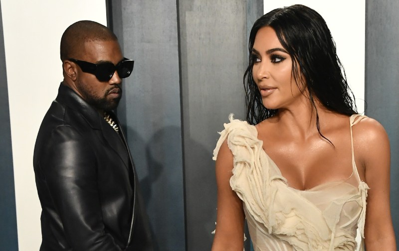 Kanye West, in black, walks up to then-wife Kim Kardashian, in a light tan dress, on the red carpet