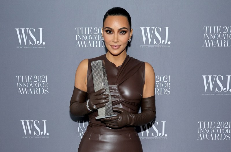Kim Kardashian in a brown dress holding an award.