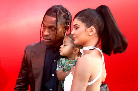 Kylie Jenner standing with Travis Scott and holding their daughter, Stormi