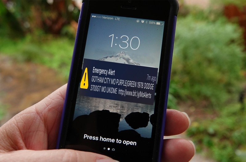 A phone with an emergency alert pop up about the the joker's car in Gotham City, MO.