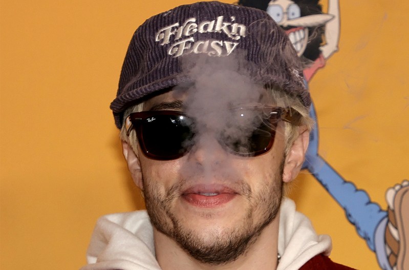 Pete Davidson wearing a hat and sunglass, in a cloud of smoke