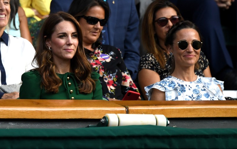 Kate Middleton, in green, sits with sister Pippa Middleton, in blue and white, at Wimbledon