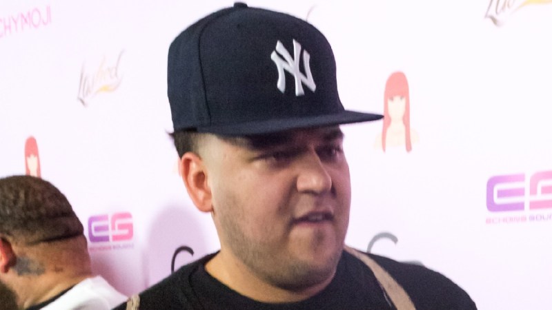 Rob Kardashian wears a black shirt and hat on the red carpet