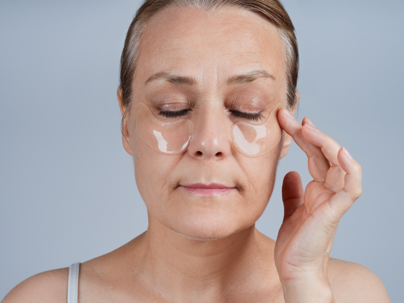Mature woman applying patches under her eyes.