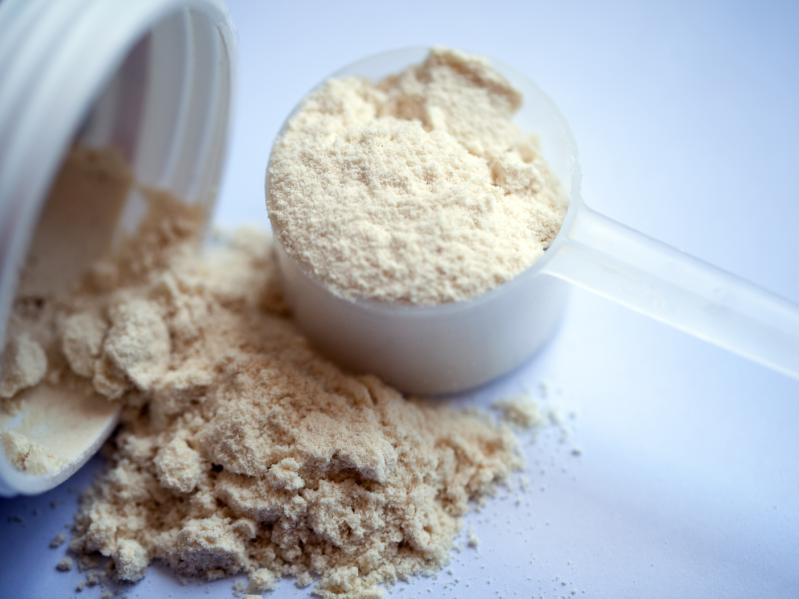 Vanilla protein powder in scoop on white background