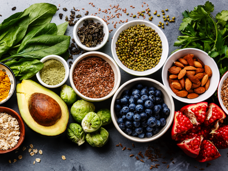 Healthy food clean eating selection: fruit, vegetable, seeds, superfood, cereal, leaf vegetable on gray concrete background