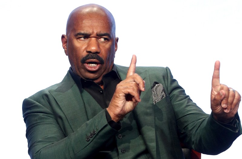 Steve Harvey looking annoyed and gesturing as if to say "hold on"