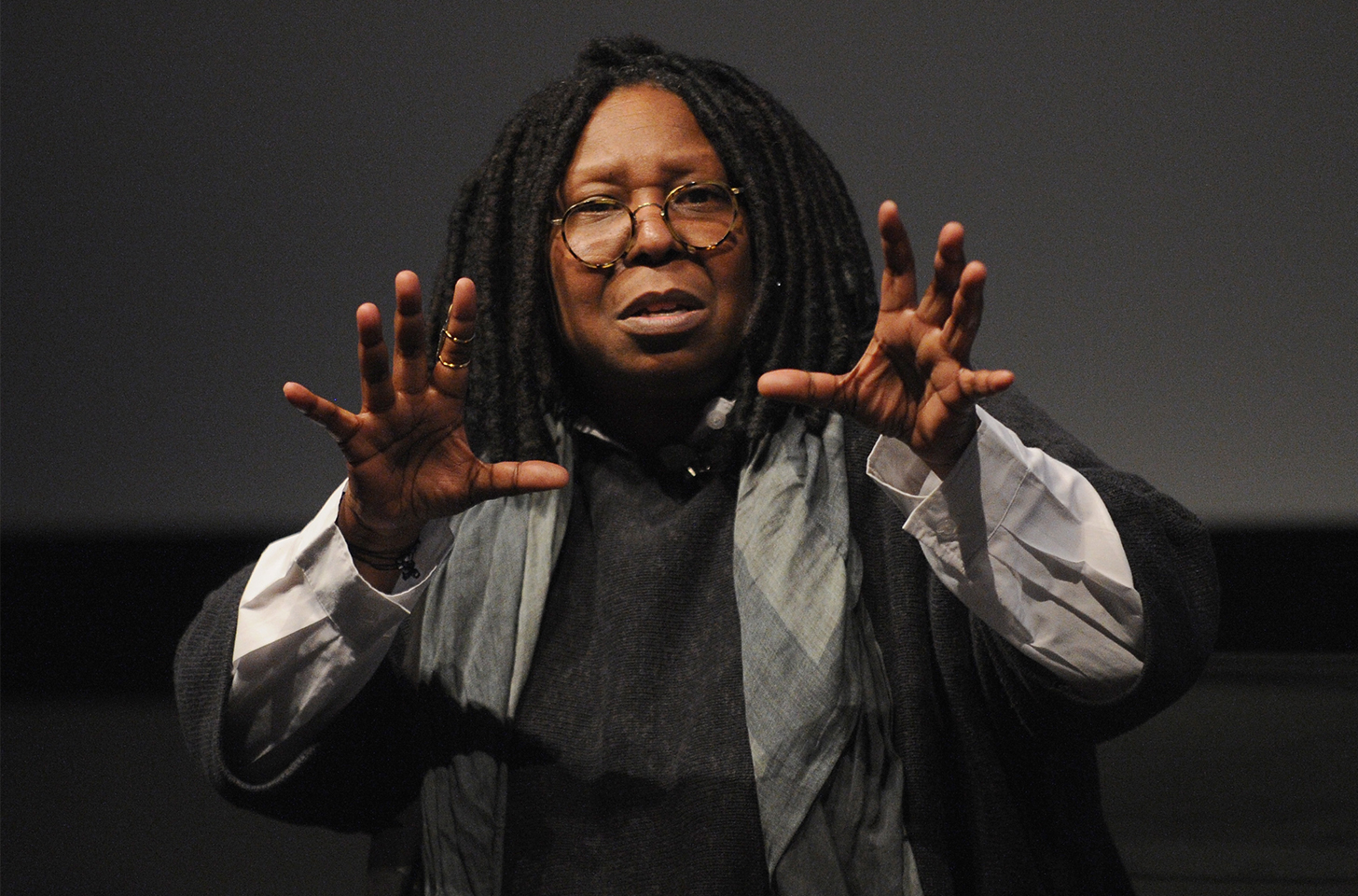 Whoopi Goldberg with her hands at shoulder height, fingers extended like she's grabbing something in the air.