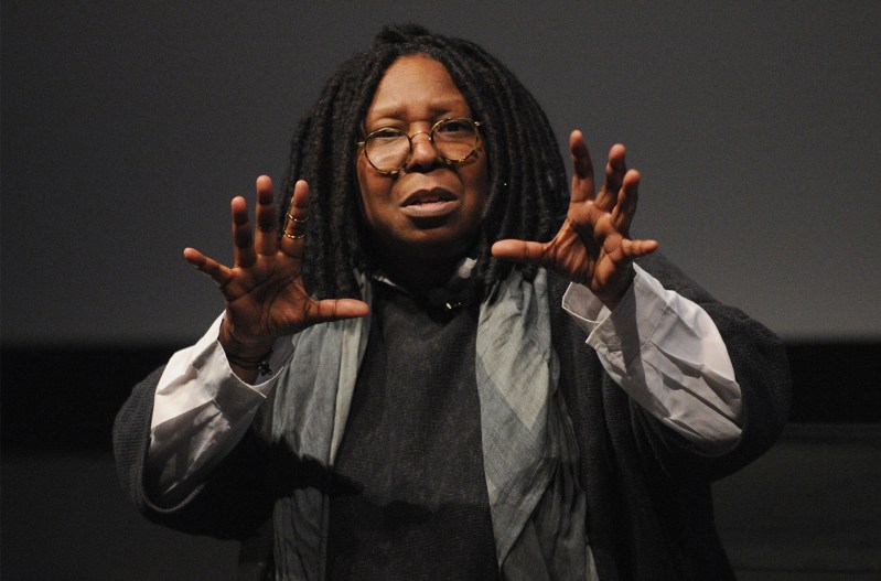 Whoopi Goldberg with her hands at shoulder height, fingers extended like she's grabbing something in the air.