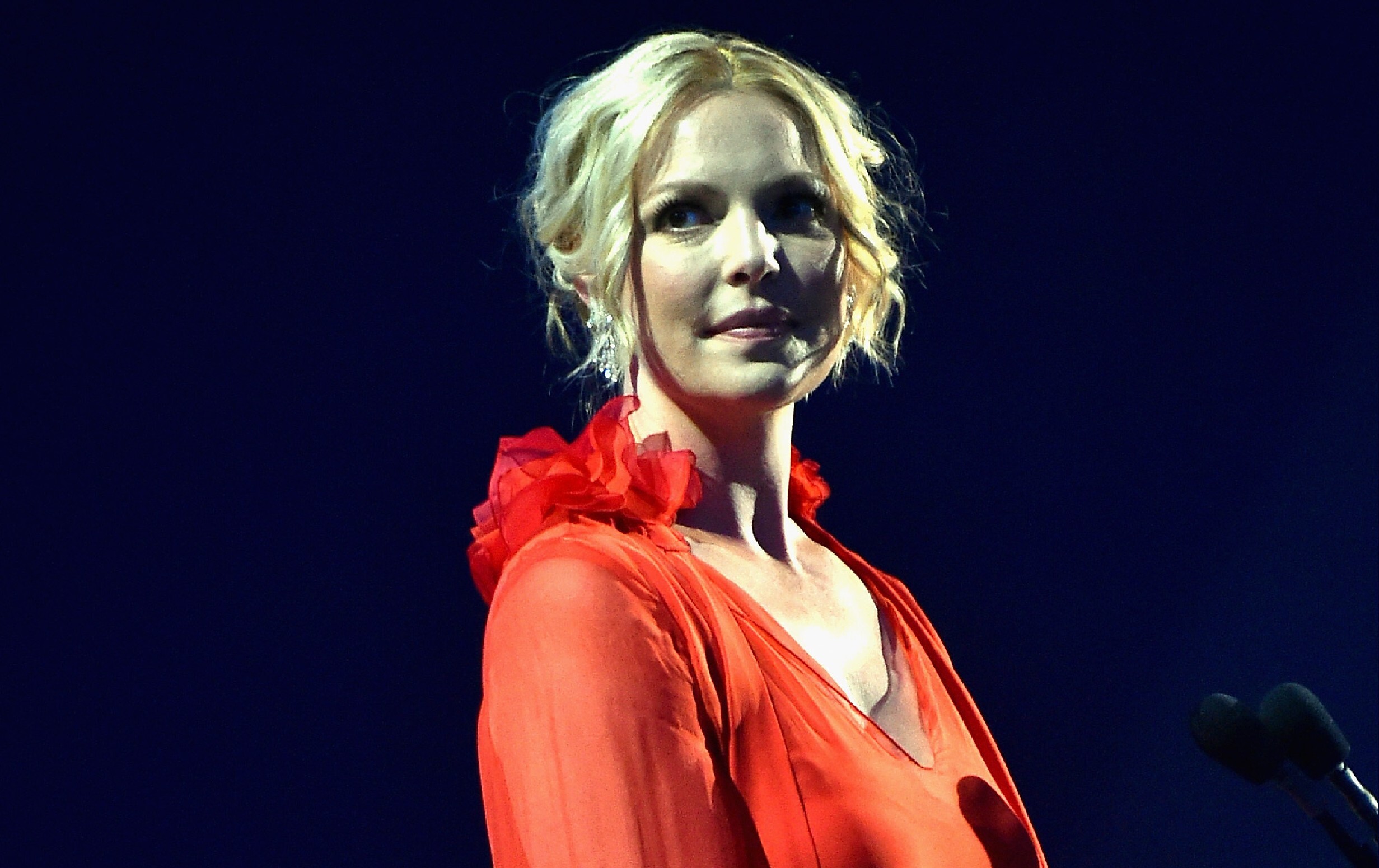 Katherine Heigl smiling with a dark background