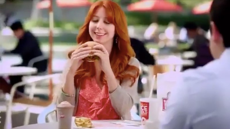 Screenshot of Morgan Smith-Goodwin in a Wendy's ad, smiling and looking at a burger