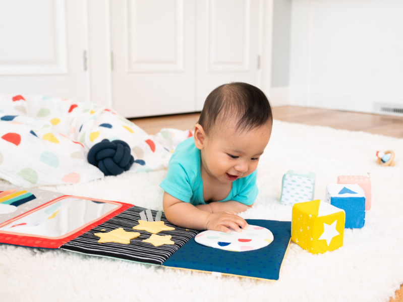 Infant playing with toy book on carpet