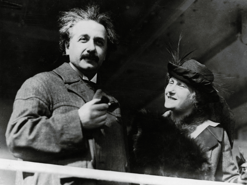 Albert Einstein and his wife standing side by side in black and white photograph
