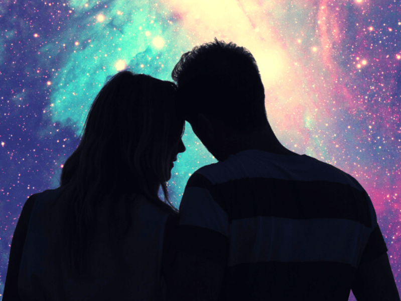 Silhouette of couple against colorful starry sky