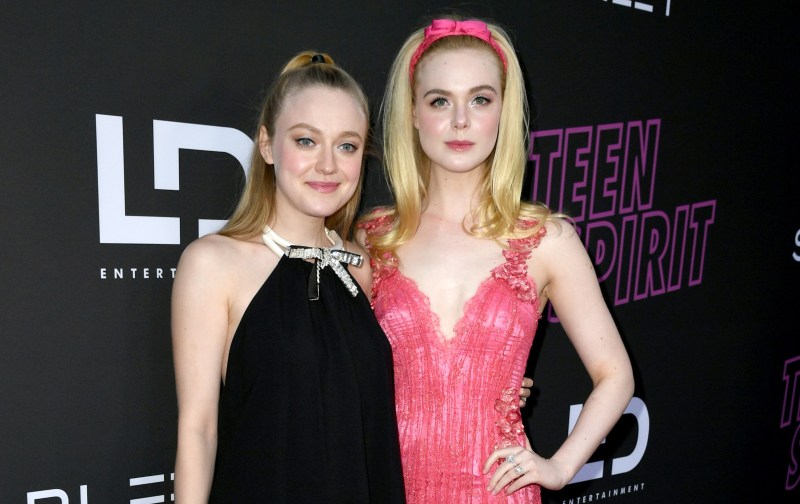 Dakota Fanning (right) wears a black dress and stands beside sister Elle, in a pink dress, on the red carpet