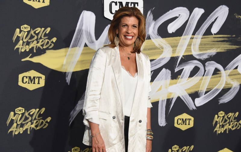 HHoda Kotb wears a white blouse under a white jacket on the CMT Awards red carpet