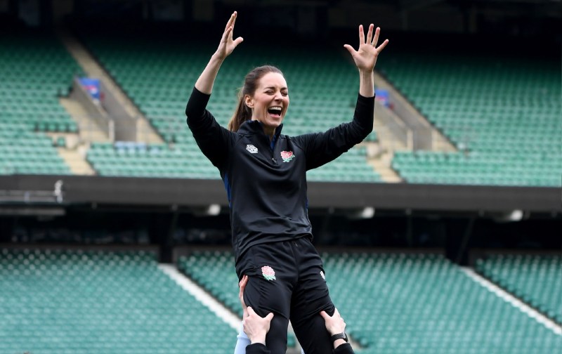 Kate Middleton wears a dark sweat suit as she's held aloft during a rugby event
