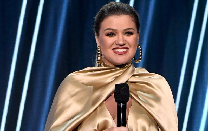 Kelly Clarkson wears a golden dress onstage at a musical awards show