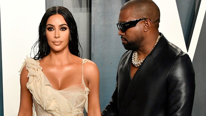 Kanye West on the right in shades, looking at Kim Kardashian on the left.