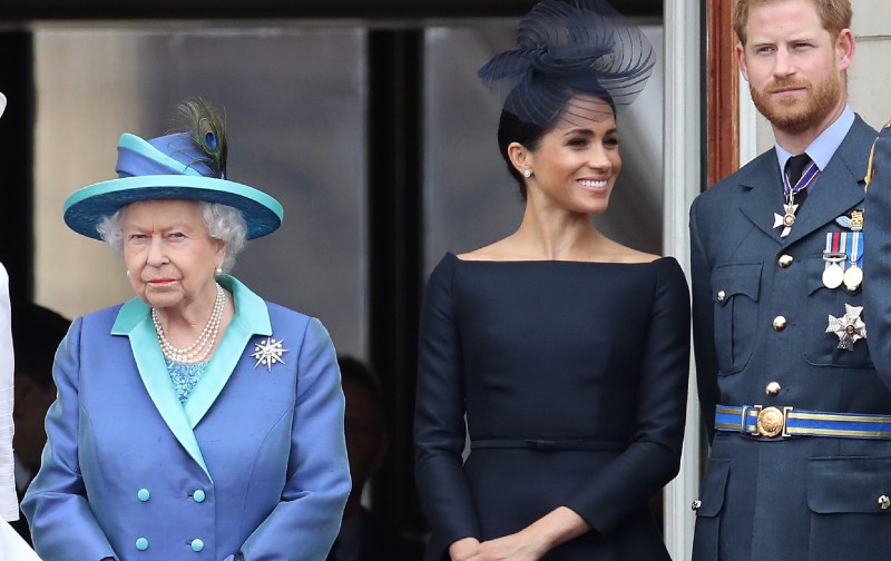Queen Elizabeth, in blue, stands with Meghan Markle and Prince Harry on a balcony